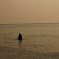 Fisherman casting a net into the sea