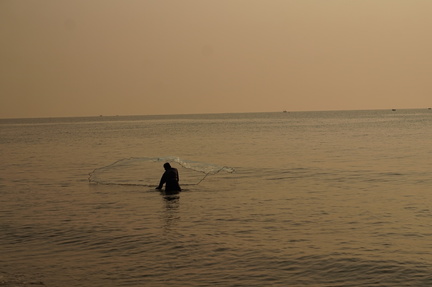 Fisherman casting a net into the sea